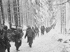 Soldiers marching down a snow covered road.
