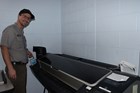 A park employee installs an ink cartridge in a large printer system in an office setting.
