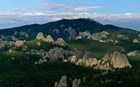 An undulating hillside of evergreen trees spiked with jagged clumps of granite peaks.