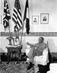 A black and white image of Dwight Eisenhower sitting in uniform reading a letter