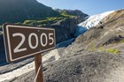 A sign reading 2005 marks where the glacier was then, the glacier is now seen in the distance.