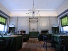 Staight angle view of the Assembly Room with empty wooden chairs and an ornate glass chandelier. 