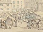 A busy market scene with people bustling around stalls.