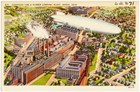 Color postcard of a silver US Navy blimp flying over the Goodyear Tire and Rubber Company plant