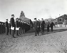 Military men stand in formation as another group walk by them