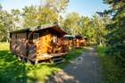 A row of symmetrical, one-story wooden cabins with porches at a slight angle to a foot path. 