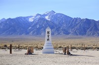 A white stone obelisk with Japanese characters stands against a backdrop of mountains.