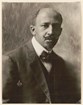 A black and white portrait of an African American man. He is seated wearing a suit and tie. 