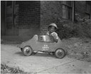 African American boy in pith helmet playing with toy car labeled US Army