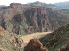 Photo of a steep walled canyon with a muddy river.