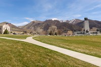A grassy park, with a sidewalk that splits through the center. Distant statues.