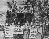 Several people standing around and in the back of a truck holding protest signs.