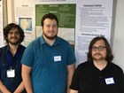 Photo of 3 people standing in front of a poster display.