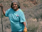 Middle aged woman standing next to agave plant with staff