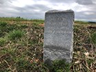 An engraved granite tablet marks the site of a battle on the farm field behind it.