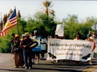 Group marching in street with sign stating 
