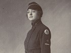 Portrait of woman in Army uniform of formal coat, long skirt, leather gloves and garrison cap.