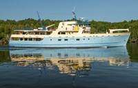 Starboard side view of the Motor Vessel Ranger III with a tree-covered island in the background