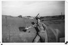 Black and white photo of a white man in coveralls in front of an airplane