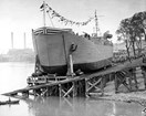 Black and white photo of a large ship with flags half on a dock