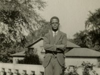 Candid portrait of a Black man standing outside on a porch.