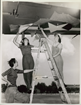 three women on or around a ladder engaged in industrial work