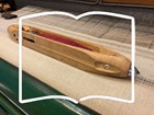 A wooden shuttle on a power loom and an oultline of an open book