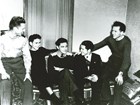Black and white photo of five men sitting on and around a couch