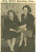 Black and white image of two women sitting examining a piece of paper