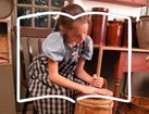 Girl with a wooden butter churn with an open book outline