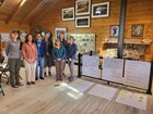 A group of writers stands next to six handwritten posters.