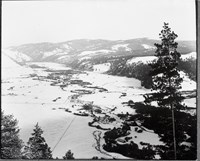 Black and white aerial photograph of a snow-covered landscape with mountains