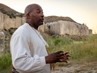 a man wearing 1800s clothing in front of tall cliffs