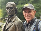 a man in a cap next to a statue of a man