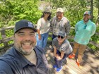 five people in hats stand in the woods