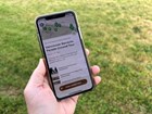 A hand holding an iPhone with the Vancouver Barracks Parade Ground tour on the screen.