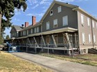 A two-story infantry barracks building, painted grey, its front porch supported by beams.