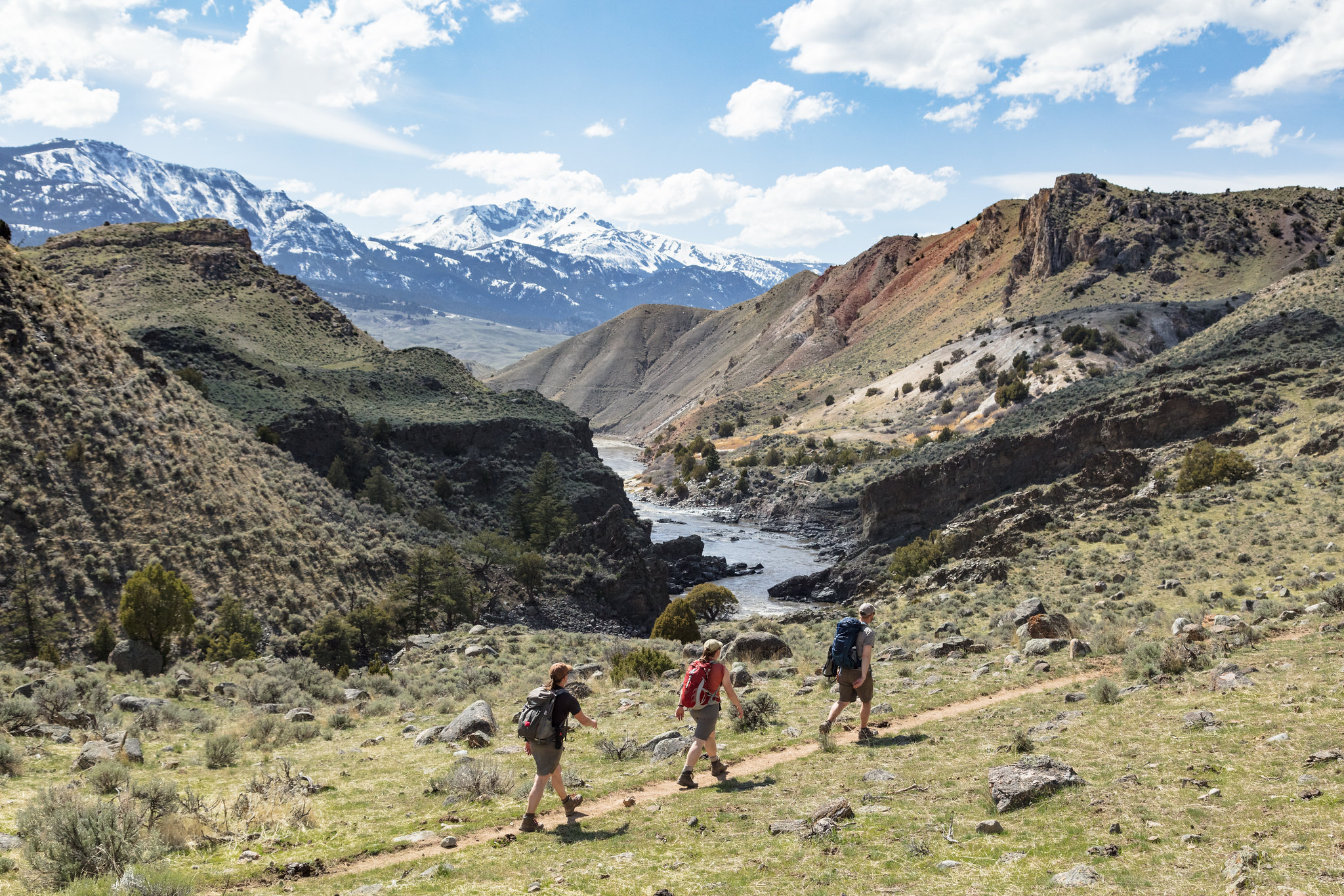 Three people on a trail with mountains in the background.