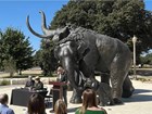 A photo of the Baylor University President speaking in front of three bronze mammoth statues