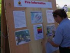 A woman uses a screwdriver on an information board.