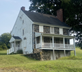 A two-story farmhouse made of field stone with a cellar. 