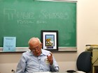 Photograph of man sitting at a desk in front of a chalkboard that says Tule Springs Fossil Beds.
