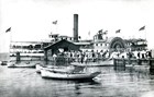 People standing on a wooden dock with a steamboat at the end.