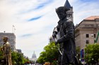 Dark bronze statue of a man in a tri-corner hat unsheathing a saber