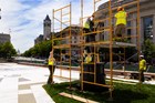 Dark bronze statue surrounded by scaffolding and workers in hard hats and hi-vis vests