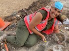 Person reclining on the ground with a fossil
