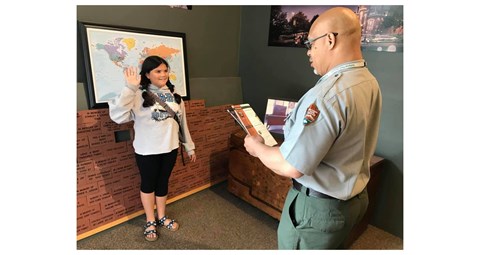A girl is sworn in by a park ranger as a junior ranger