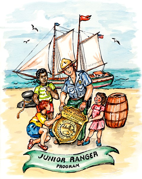 NPS Ranger with 3 kids around an enlarged Jr. Ranger Badge on a beach with a ship in the background