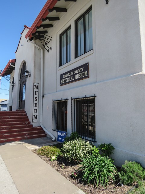 Color photograph of a solid white structure. A sign reads “museum” near the entrance.