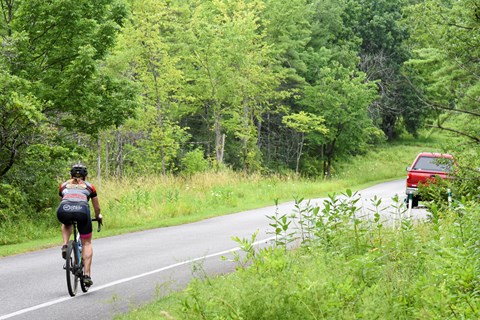Single cyclist using the bike lane of a paved road while wearing proper safety gear